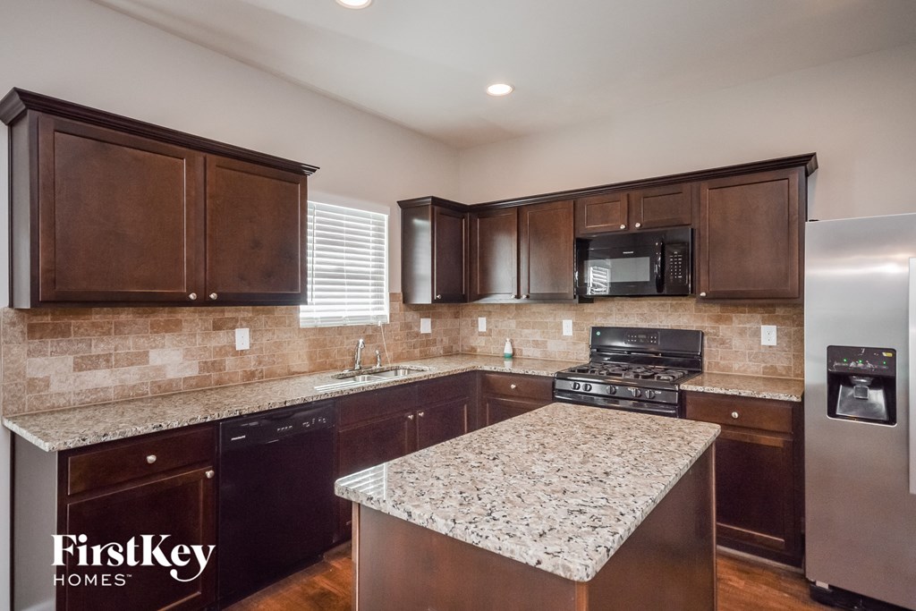 a kitchen with dark wood cabinets and granite counter tops and a sink