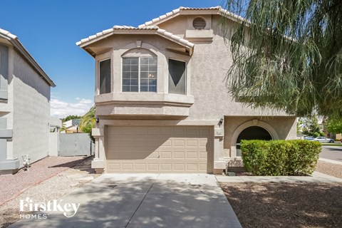 a side view of a beige house with a garage and a tree