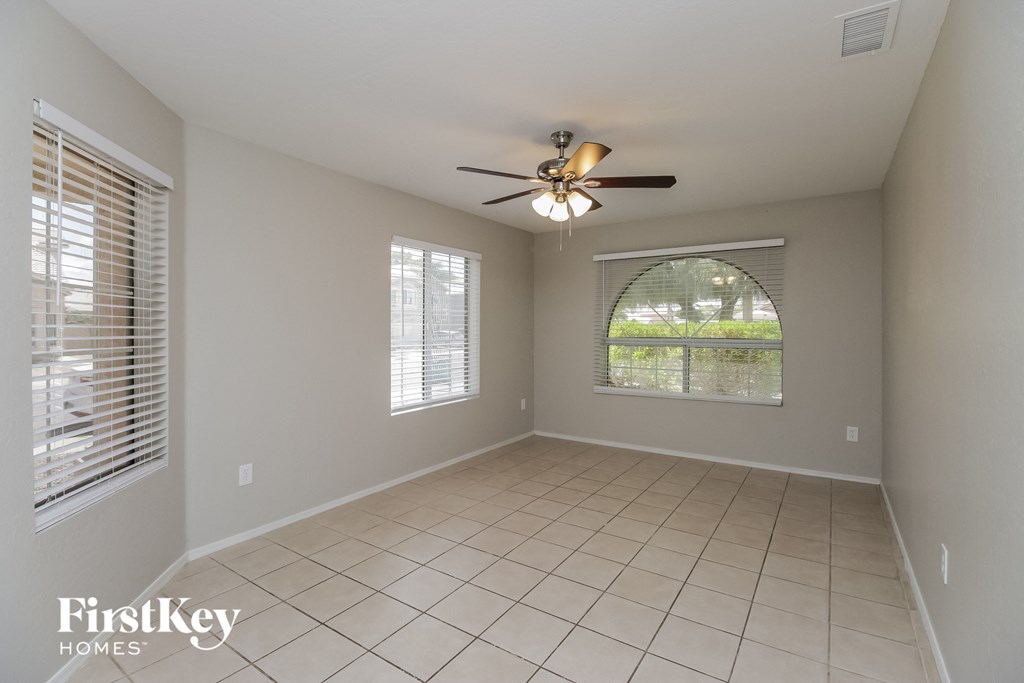an empty living room with a ceiling fan and a window