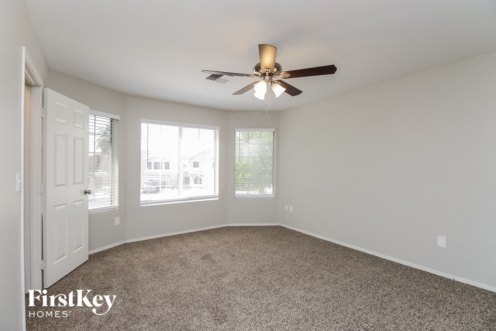an empty living room with a ceiling fan and a window