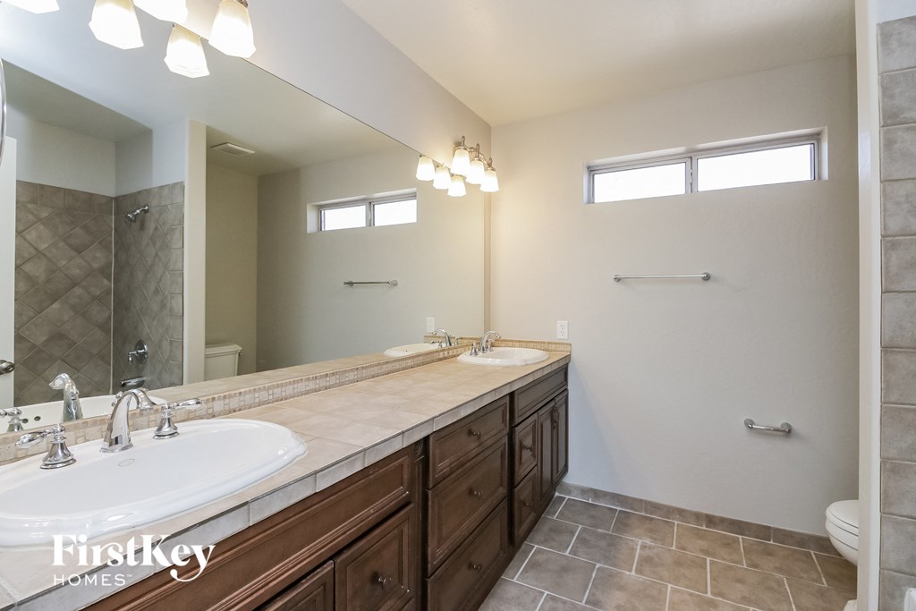 the master bathroom has dual sinks and a large mirror