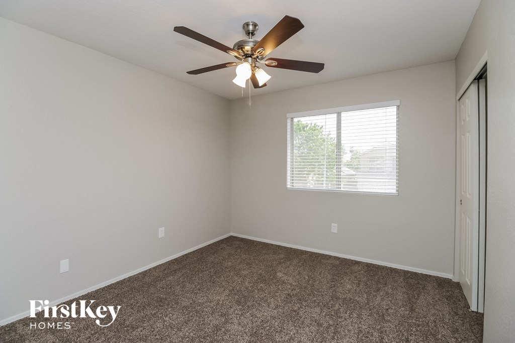 the spacious living room with ceiling fan and carpeting