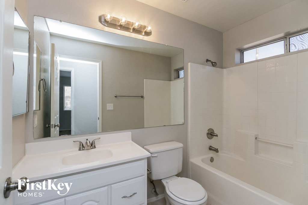 a white bathroom with a large mirror and a white sink and toilet