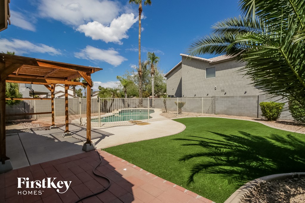 a backyard with a fenced in pool and a house