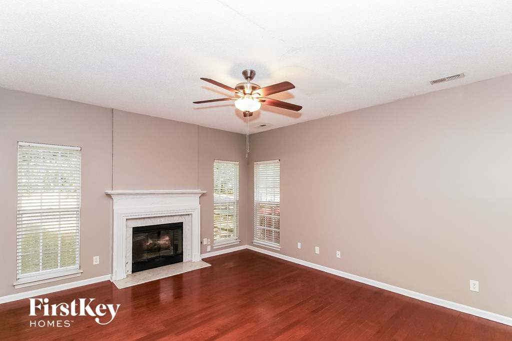 A spacious room with a fireplace and a ceiling fan.