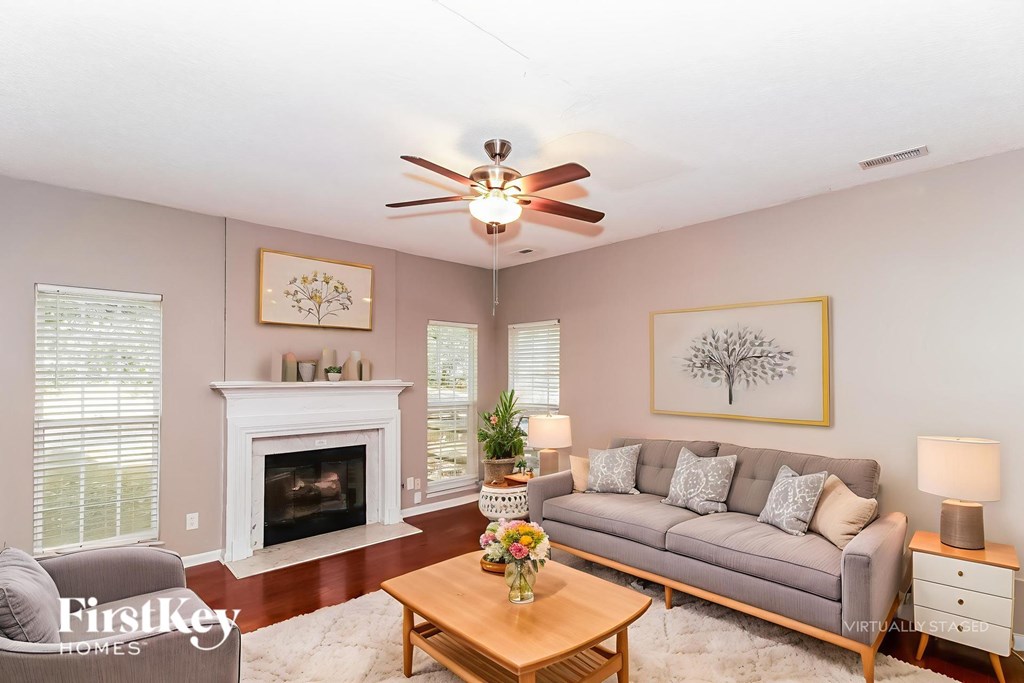 A living room with a fireplace, a couch, a coffee table, and a ceiling fan.