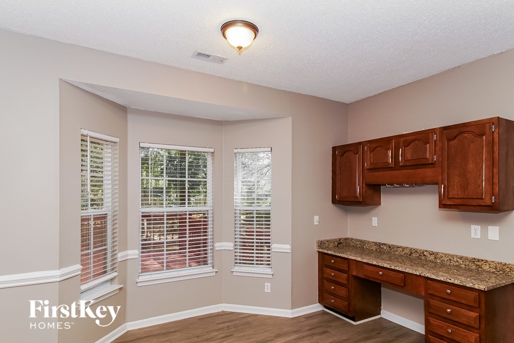 A room with a desk and a window with blinds.