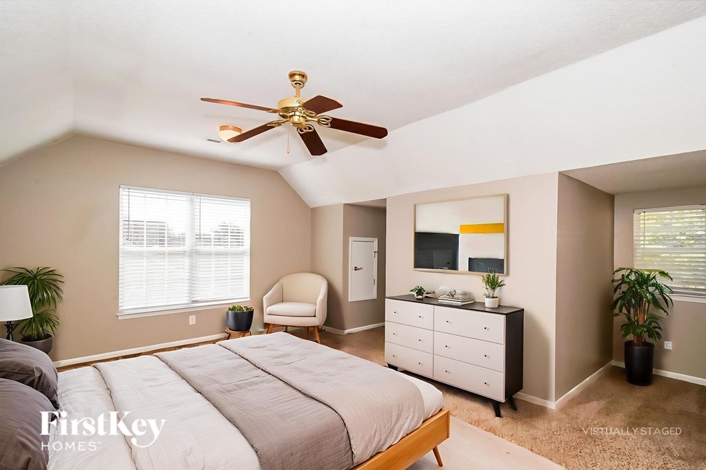 A bedroom with a bed, dresser, and ceiling fan.
