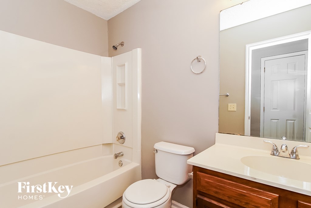 A white toilet sits next to a white bathtub in a bathroom.