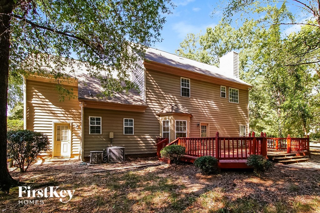 A house with a red fence and a yellow door is surrounded by trees.