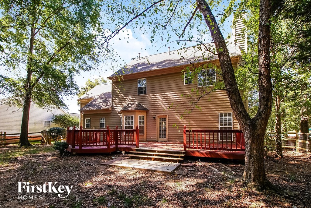 A house with a red deck is surrounded by trees.