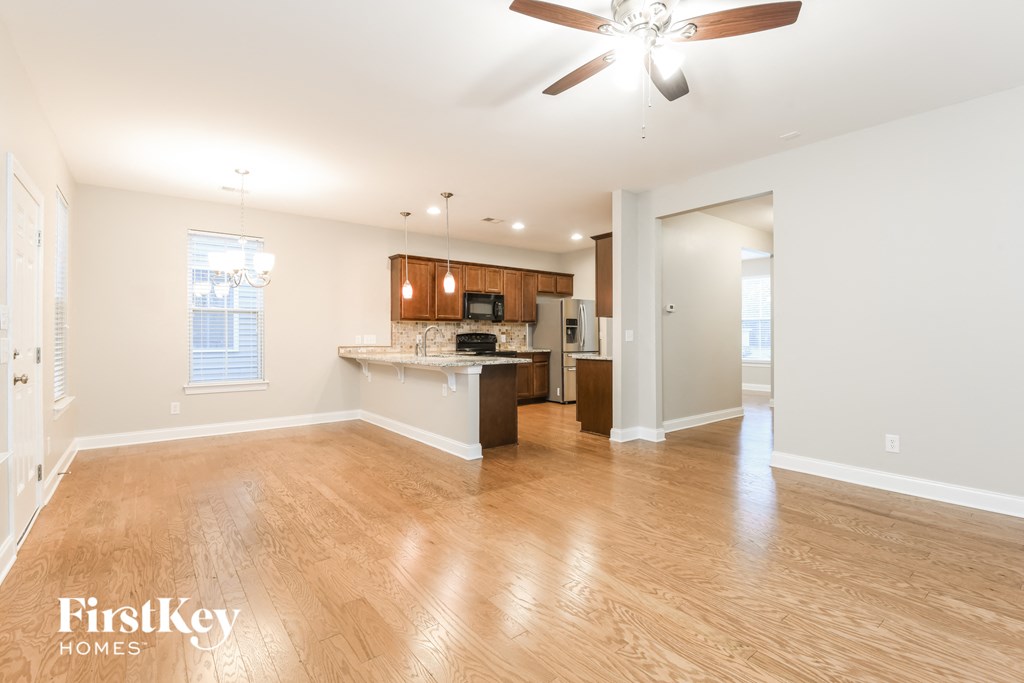 an empty living room and kitchen with wood floors and a ceiling fan