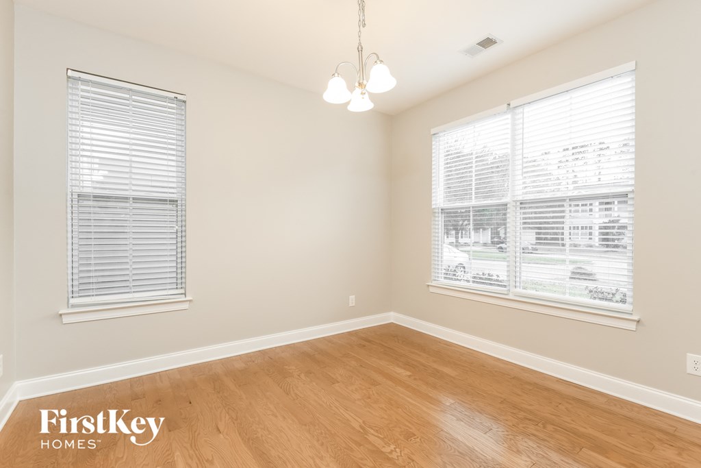 a bedroom with a wood floor and two windows