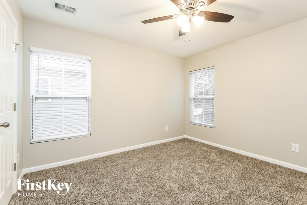 a bedroom with carpet and a ceiling fan and two windows