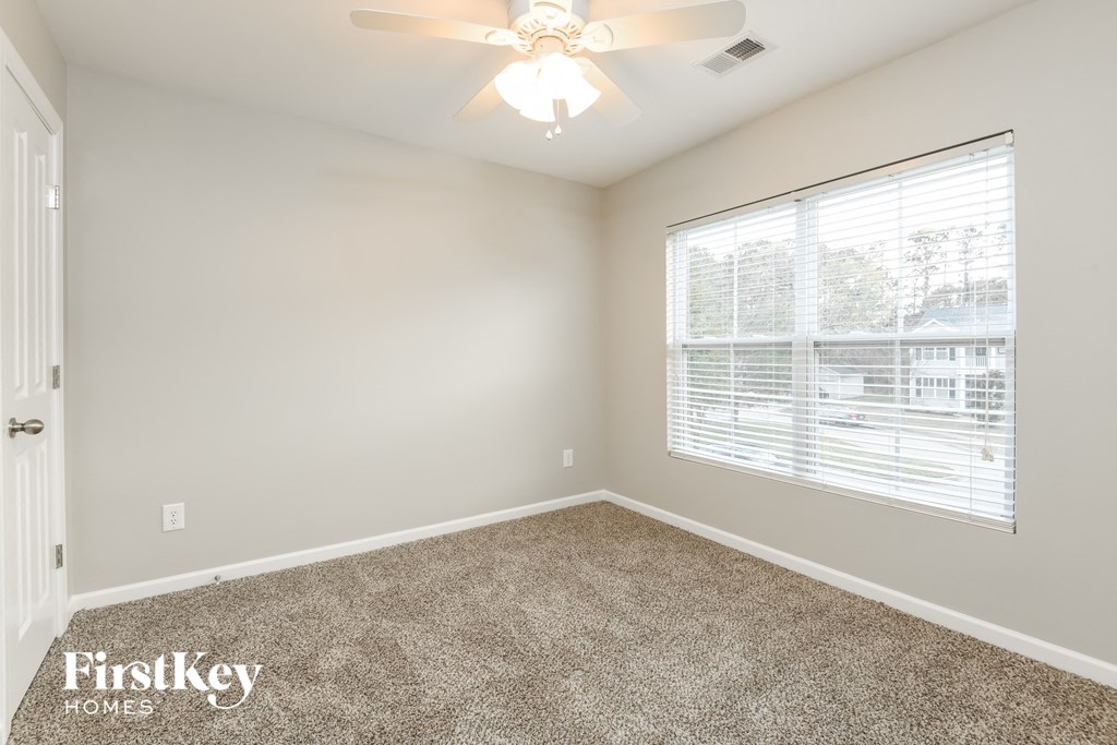 a bedroom with a large window and a ceiling fan