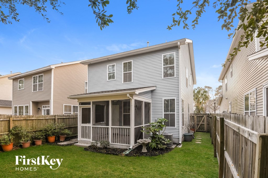 the back of a house with a yard and a wooden fence