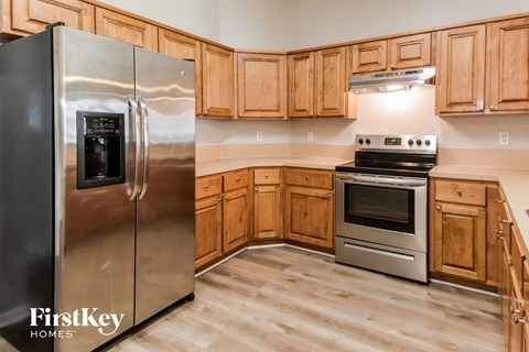 A kitchen with wooden cabinets and a stainless steel refrigerator.
