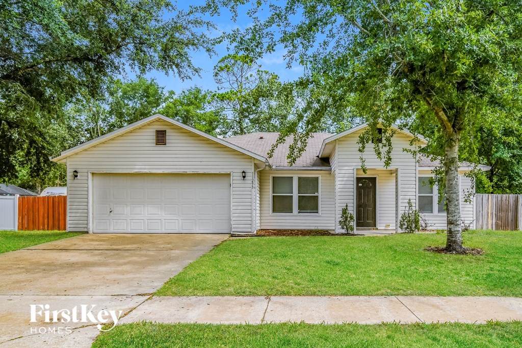 A house with a garage and a tree in front.