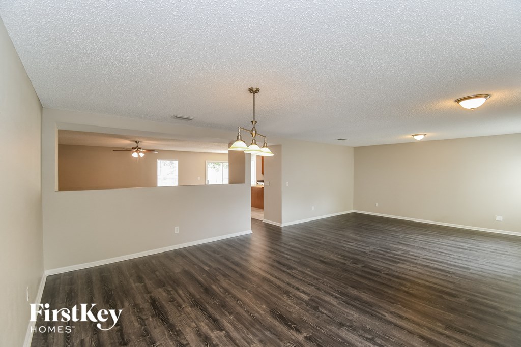 A large empty room with wooden floors and a chandelier hanging from the ceiling.