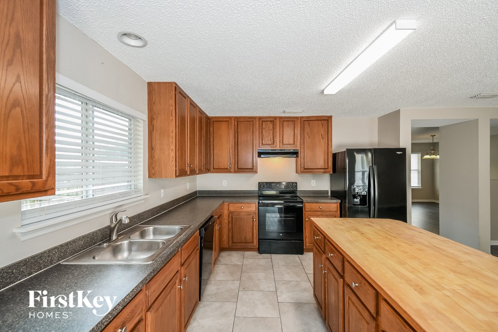 A kitchen with wooden cabinets and a black refrigerator.