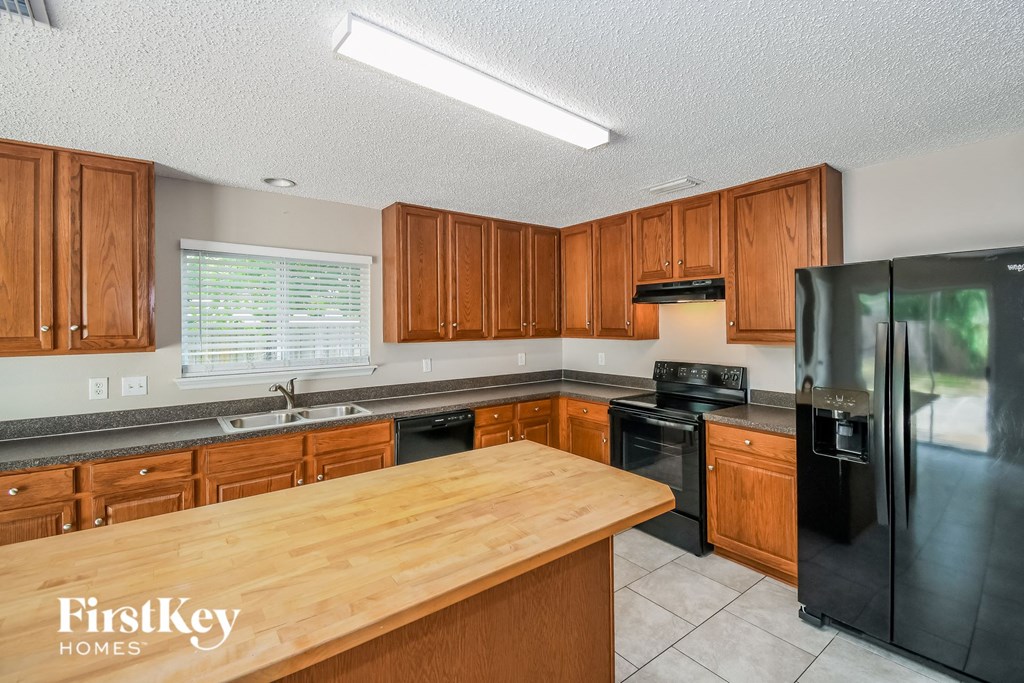 A kitchen with wooden cabinets and a black refrigerator.