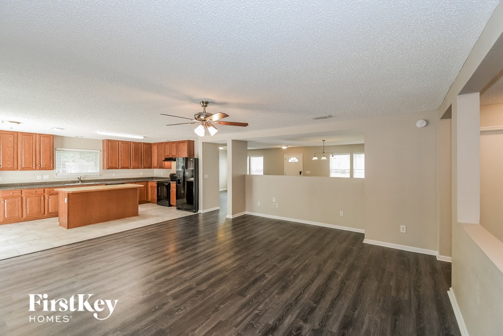 A spacious living room with wooden flooring and a ceiling fan.