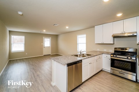 A kitchen with white cabinets and a granite countertop.