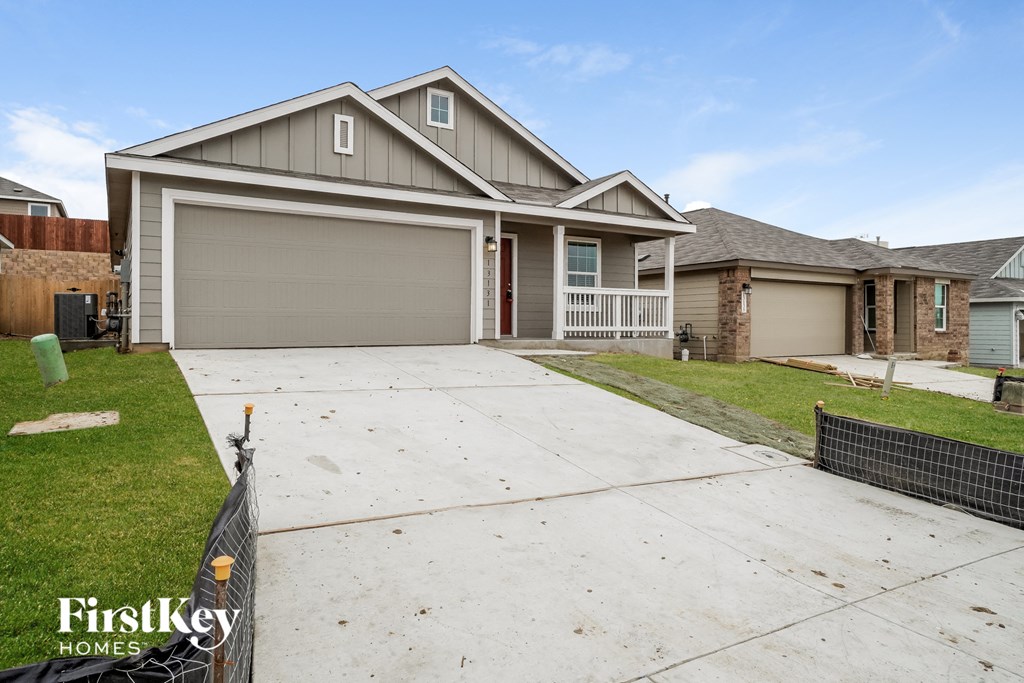 A house with a garage and a fence in front of it.