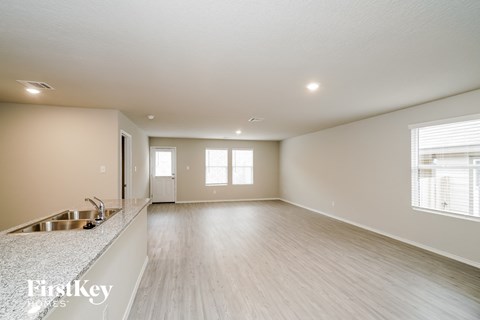 A spacious room with wooden flooring and a kitchen area with a sink.
