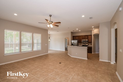 A spacious living room with a kitchen in the background.