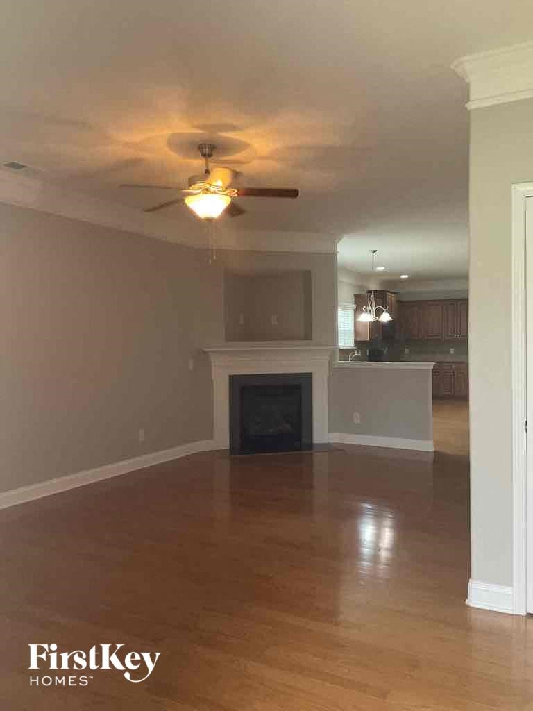 an empty living room with a ceiling fan and a fireplace