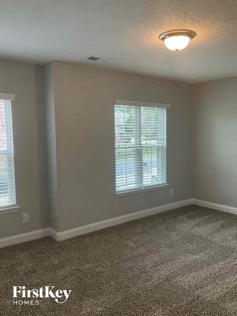 an empty living room with a carpeted floor and two windows