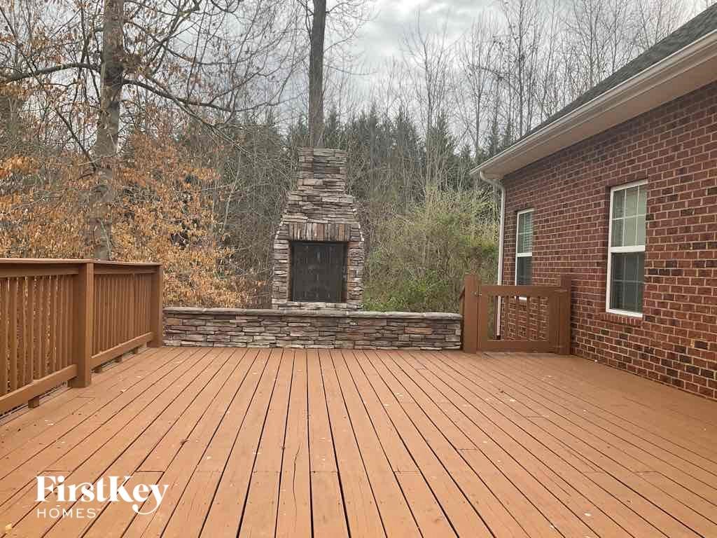 a large deck with a brick fireplace and a wooden fence