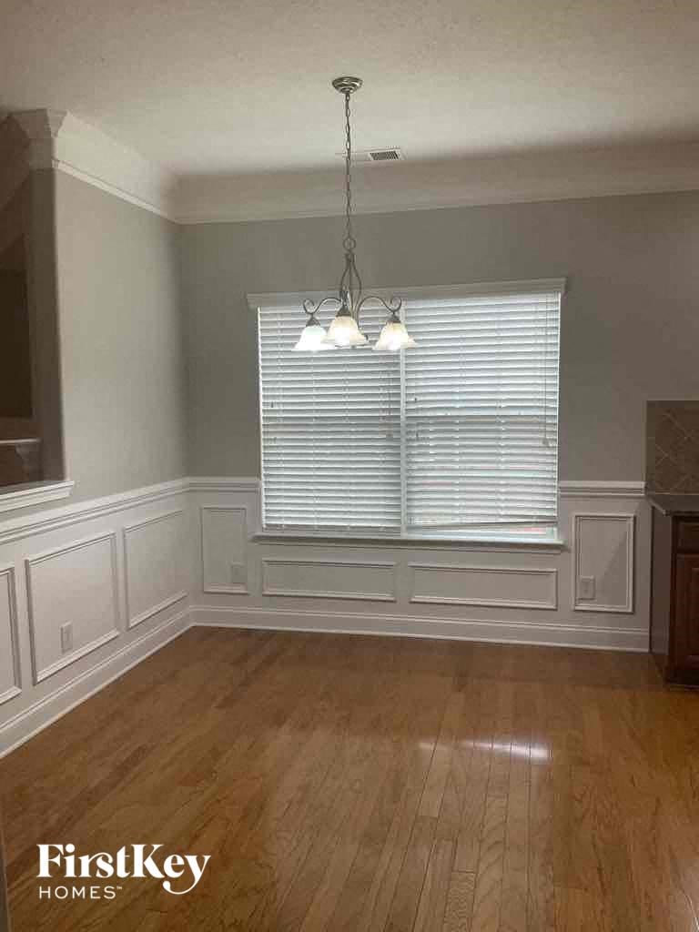 an empty dining room with wood floors and a window