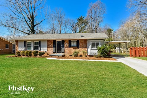 a small brick house with a lawn and a sidewalk