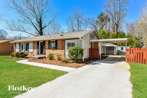 a small brick house with a white sidewalk in front of it