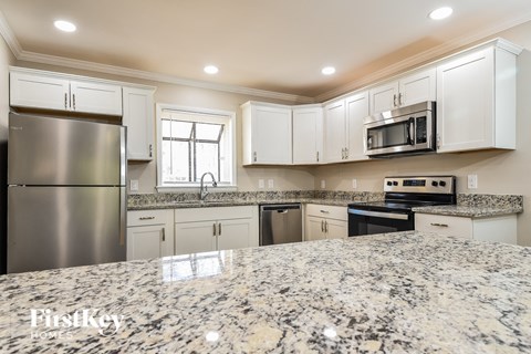 an updated kitchen with granite counter tops and white cabinets
