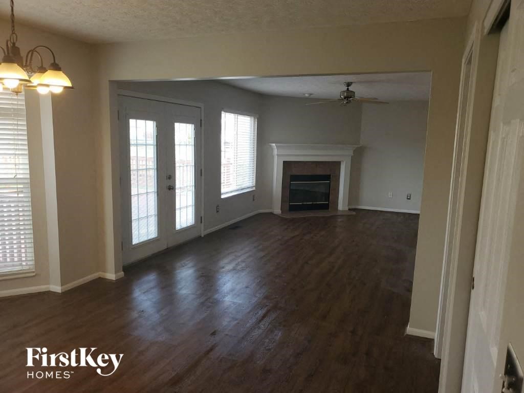 an empty living room with a fireplace and wood floors