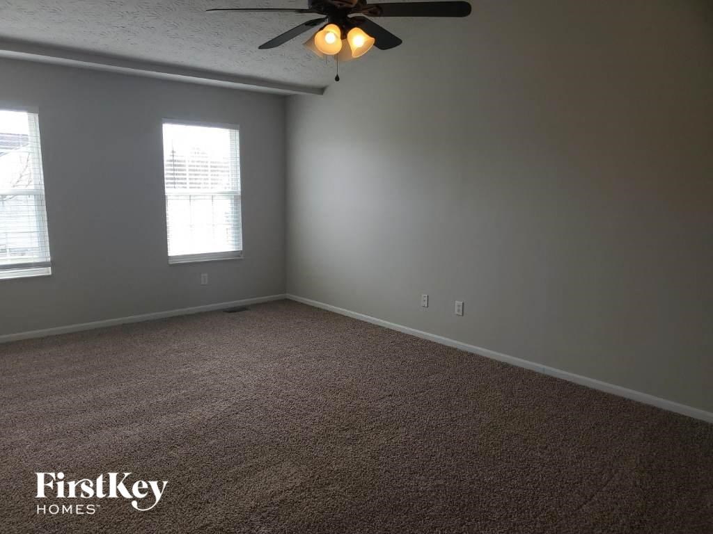 an empty room with a ceiling fan and two windows