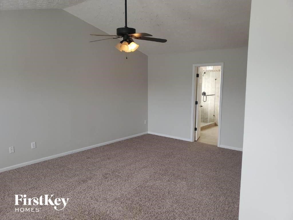 a living room with a ceiling fan and a carpet