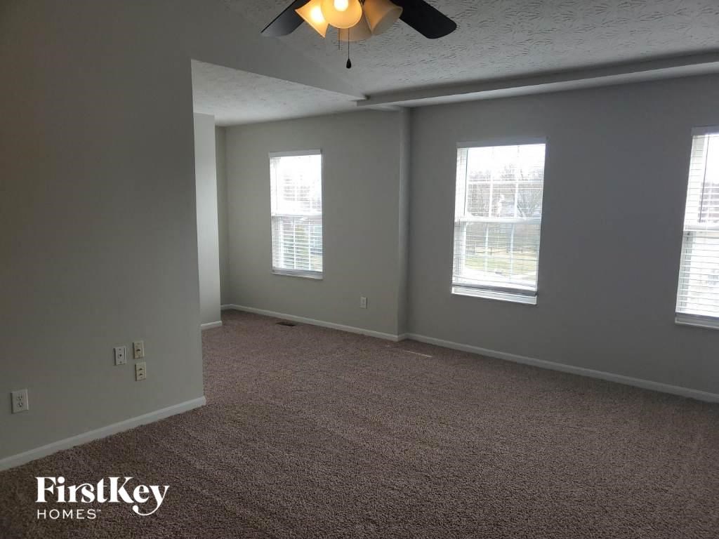 an empty room with a ceiling fan and three windows