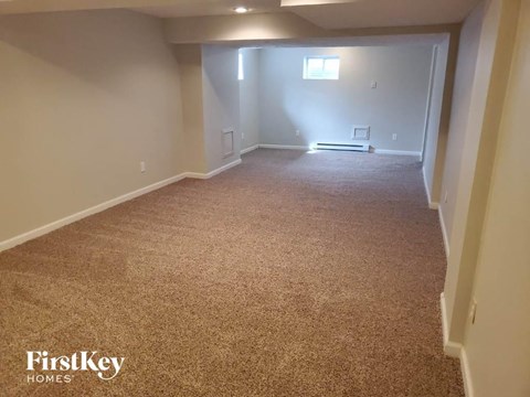 a carpeted room with a white wall and a window