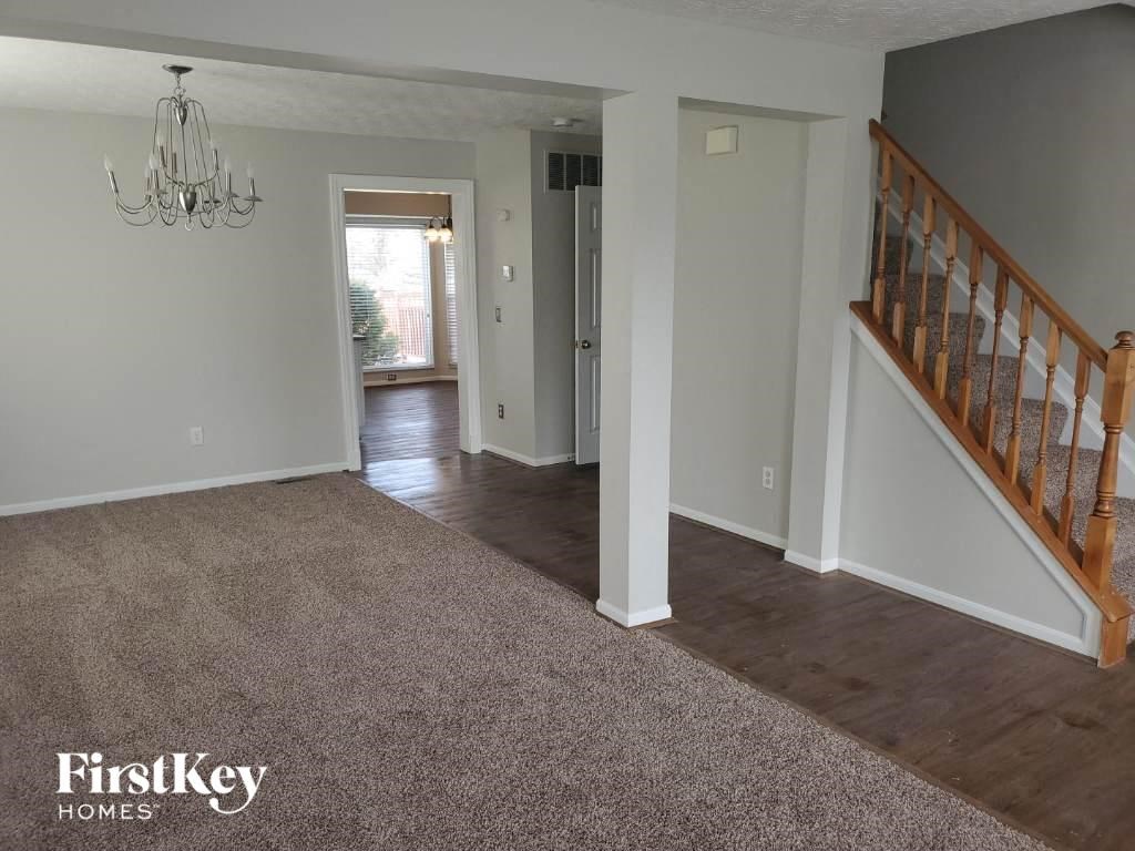 a living room with a staircase and a carpeted floor