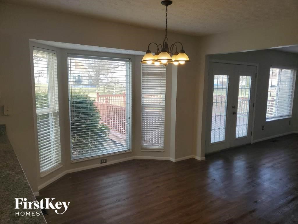 an empty living room with large windows and a chandelier