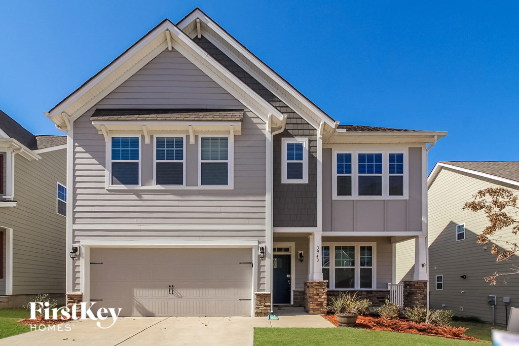 a beige and gray house with a sidewalk in front of it