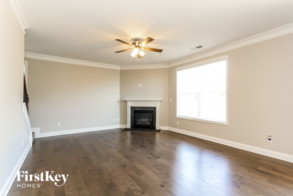 an empty living room with a fireplace and a ceiling fan