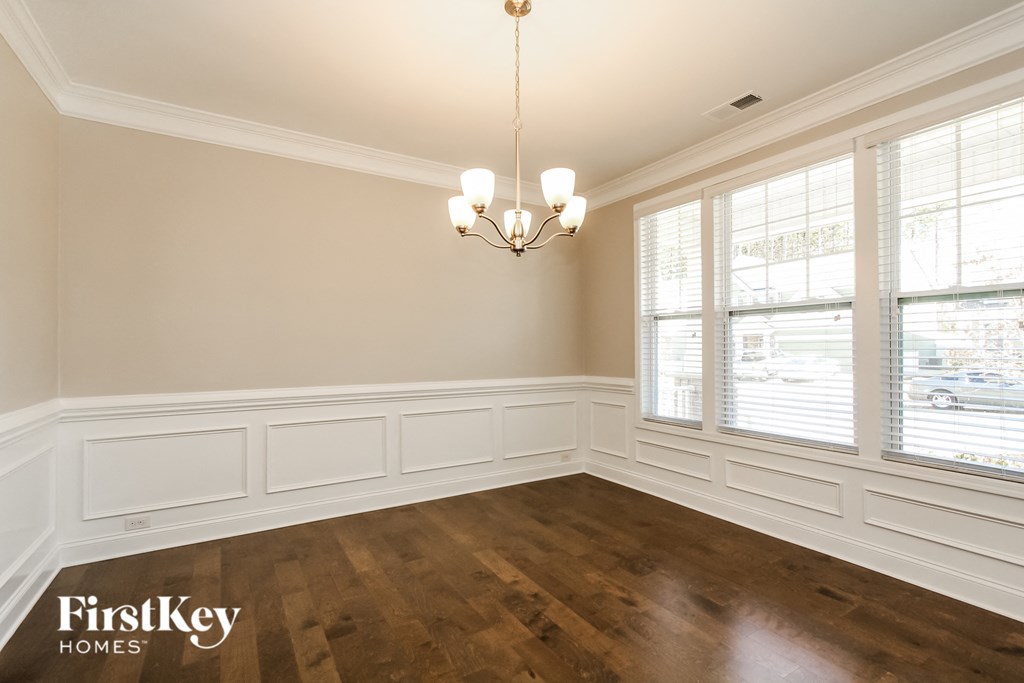 the dining room of a house with wood floors and a chandelier