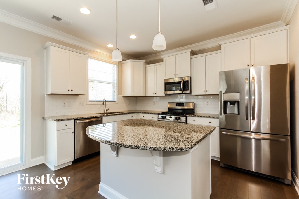 a kitchen with white cabinets and granite counter tops and stainless steel appliances