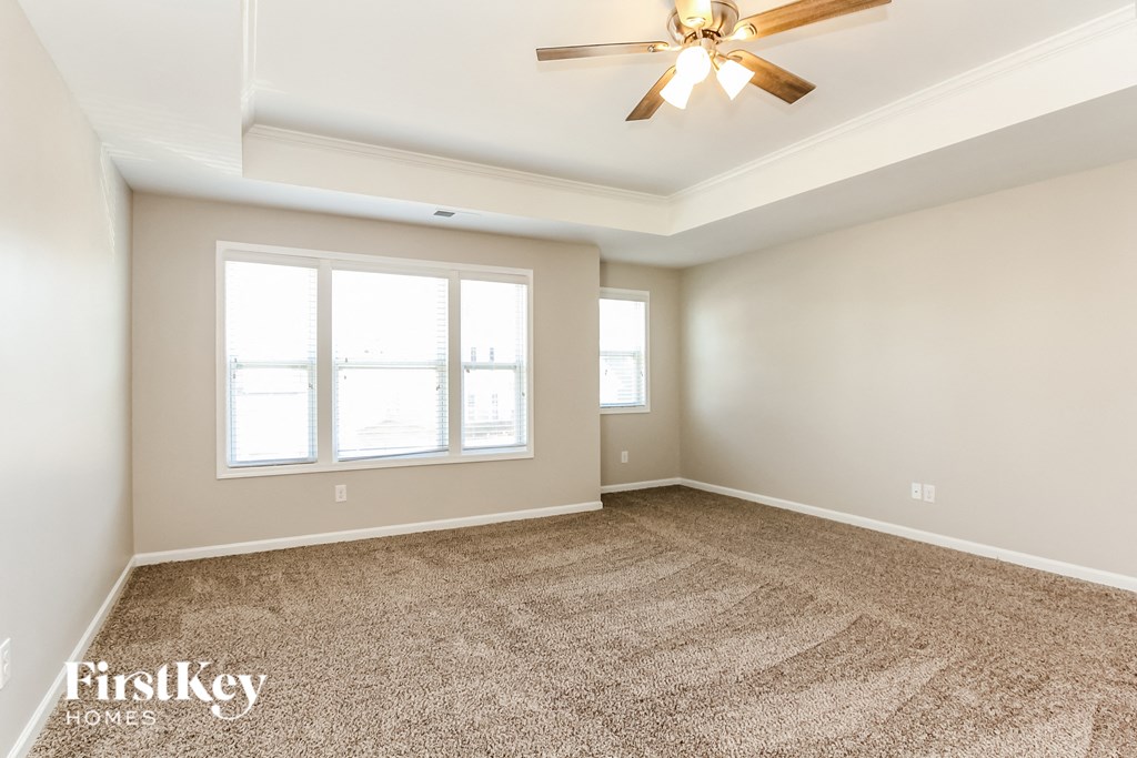 an empty living room with a ceiling fan and a window