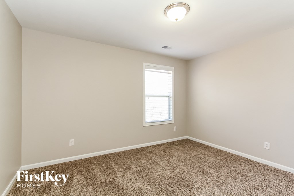 the spacious living room with carpeting and a window